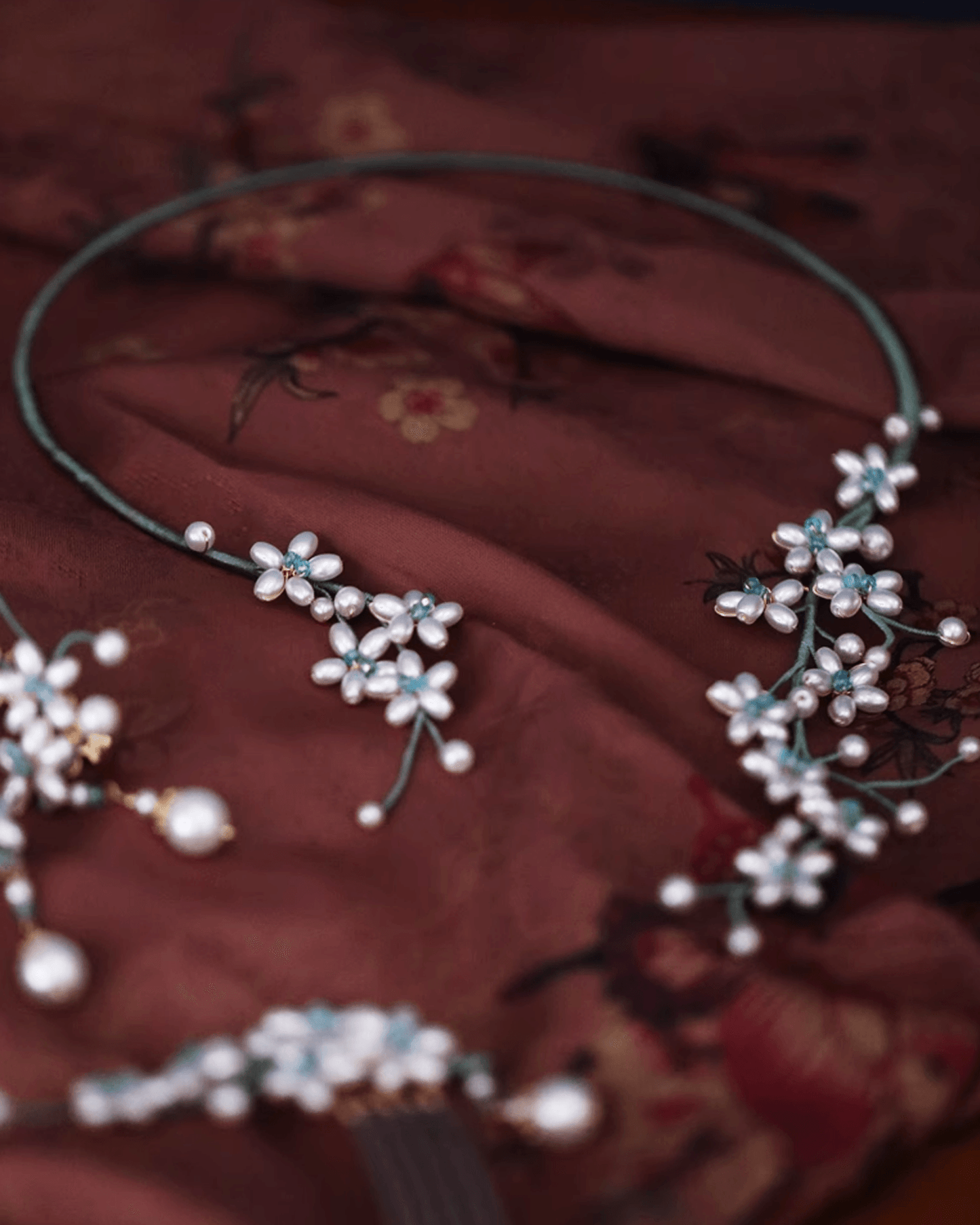 Shell pearl choker resting on silk scroll with brush painting, evoking garden aesthetics of classical China