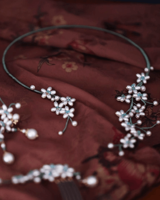 Shell pearl choker resting on silk scroll with brush painting, evoking garden aesthetics of classical China