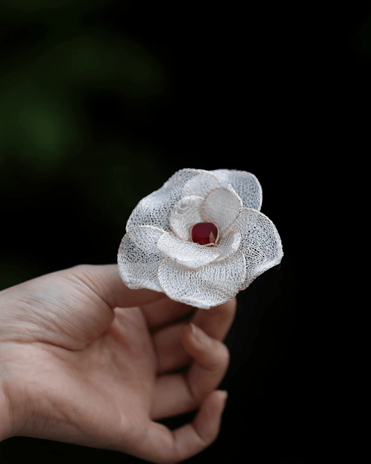 Close-up of handwoven camellia brooch with mother-of-pearl petals and luminous textures