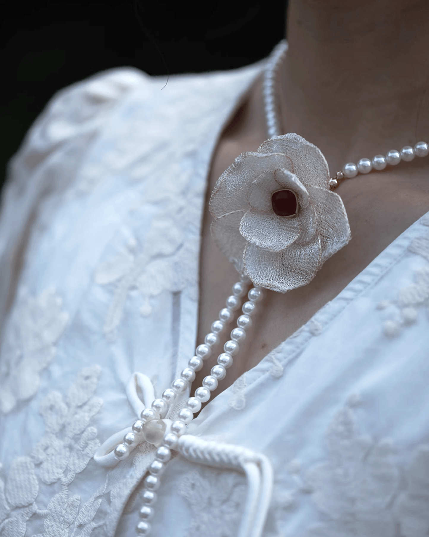 Layered styling with camellia brooch and pearl necklace for beach wedding ensemble, reflecting cultural romance