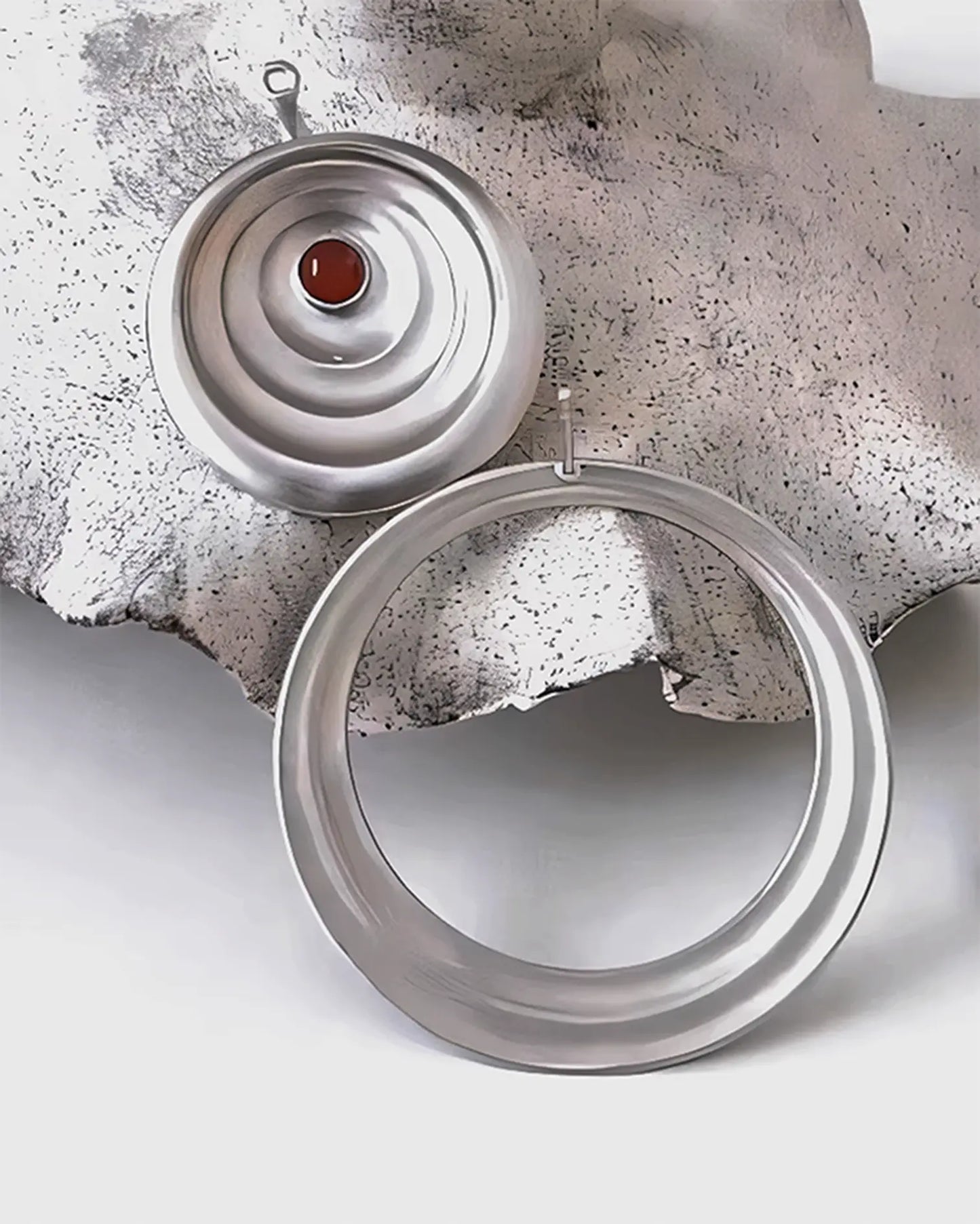 Close-up of detachable silver earring stud showing precise hand-engraved water ripple pattern and smooth polished edges