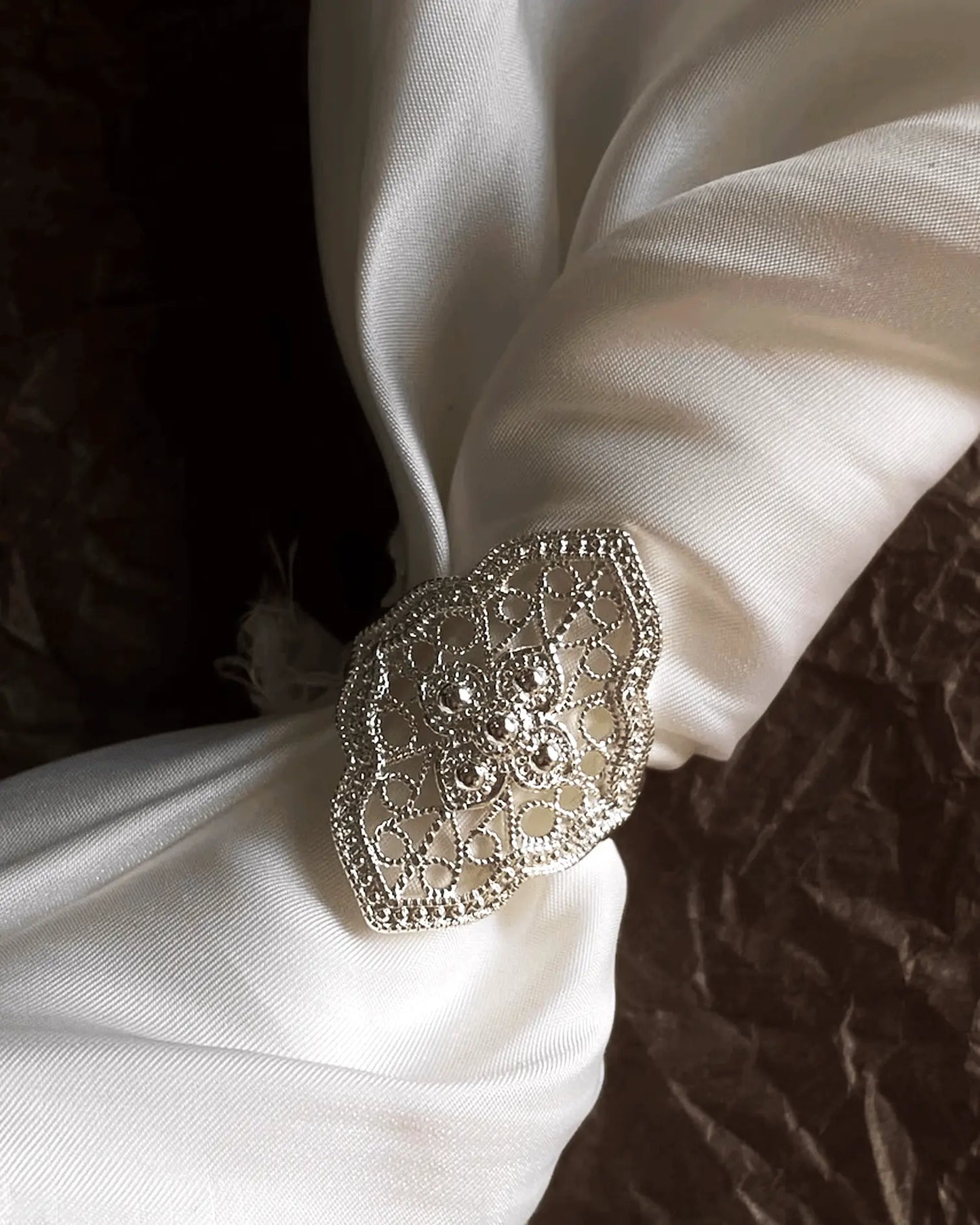 Flat lay of sterling silver lattice ring with openwork design inspired by Yi ethnic patterns, symbolizing harmony between heaven and earth