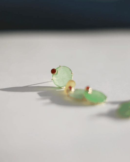 Close-up of translucent chalcedony discs stacked along engraved gold pillar with red carnelian bead accent