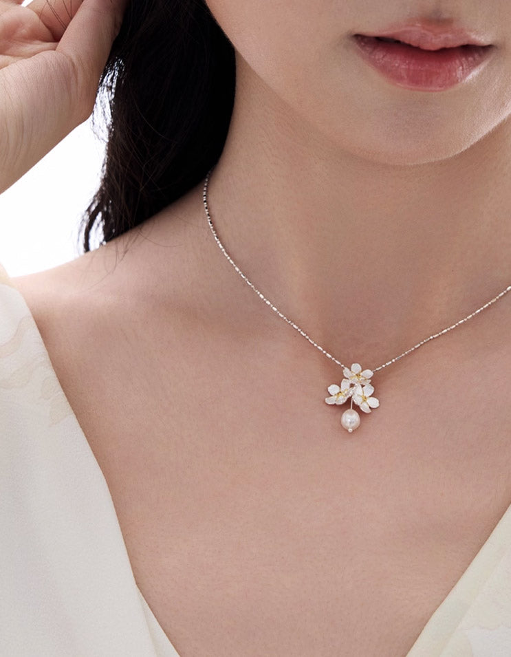 Detailed view of the jasmine-inspired sterling silver pendant paired with a natural freshwater pearl.