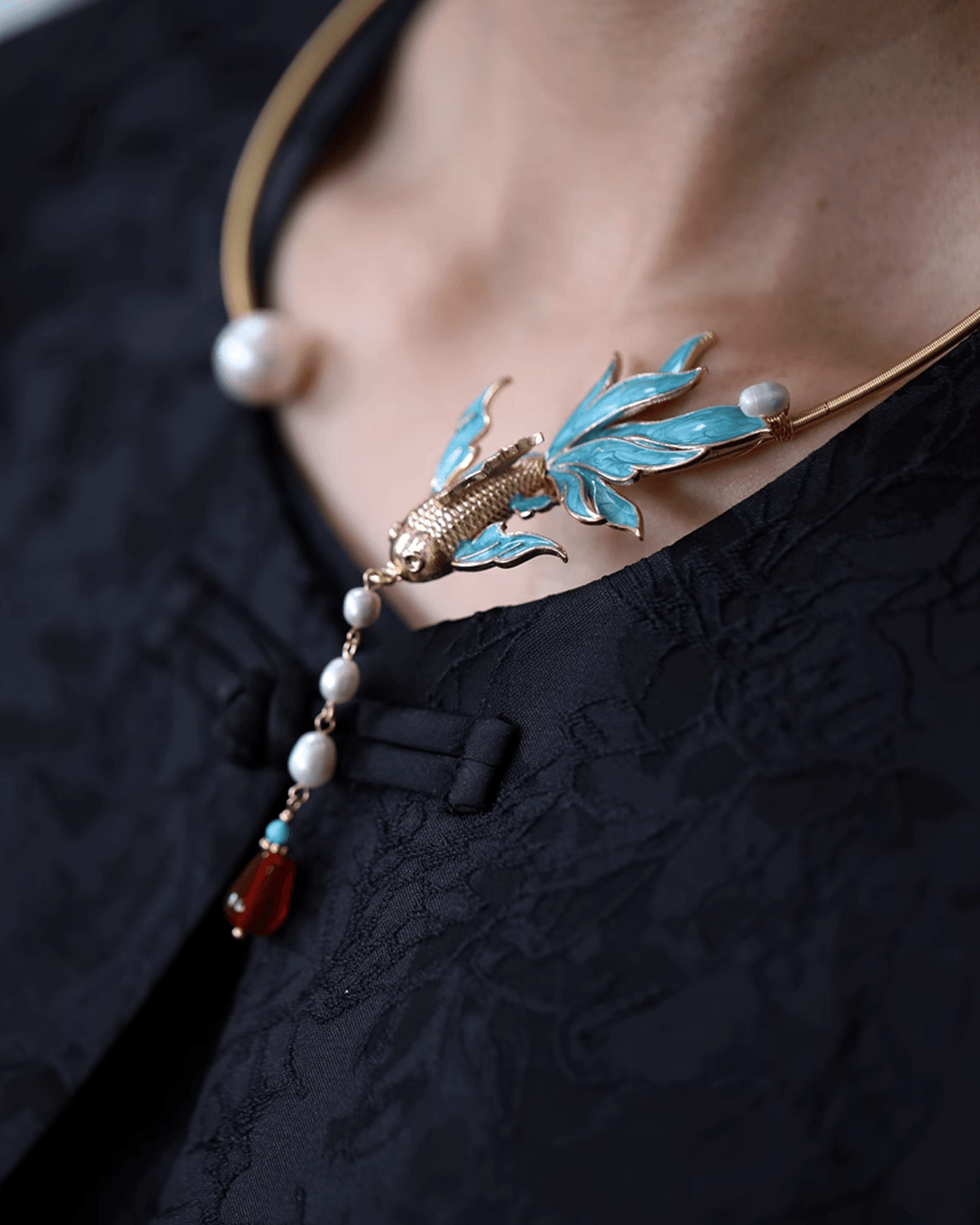 Close-up of enamel fish choker glowing under natural light, worn with minimalist silk blouse