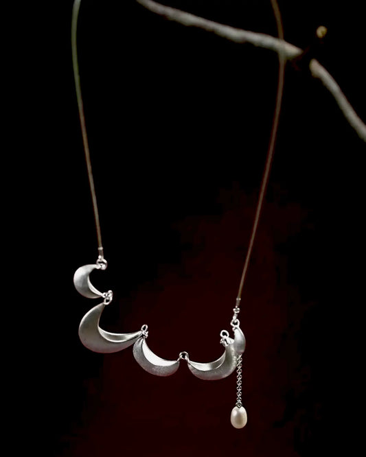 Detail of adjustable silver chain (16''–24'') with crescent charms, transitioning from choker to statement piece