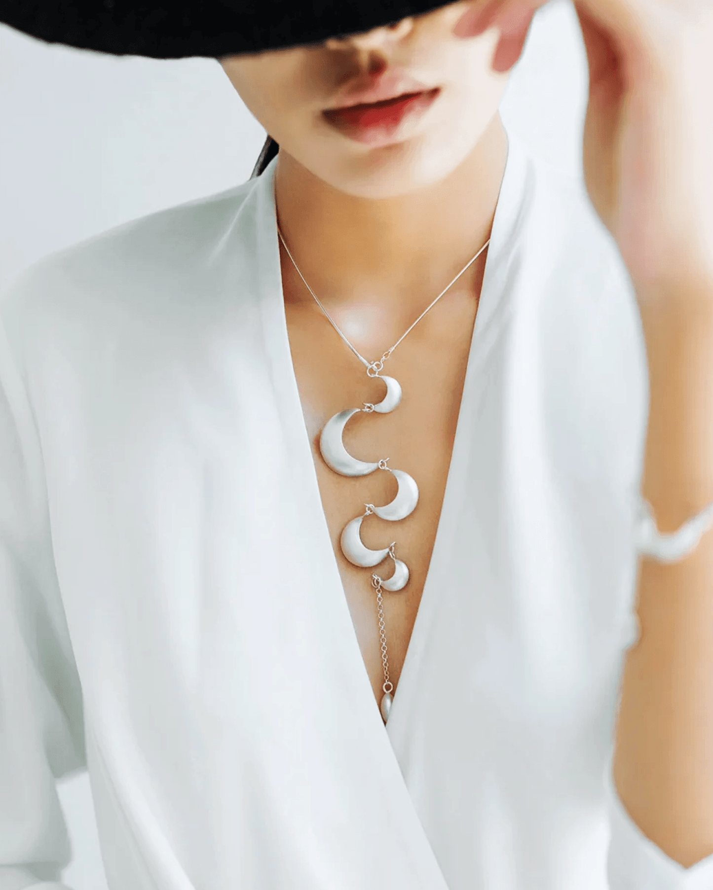 Close-up of silver crescents resting on collarbone, tassels moving gently with each step