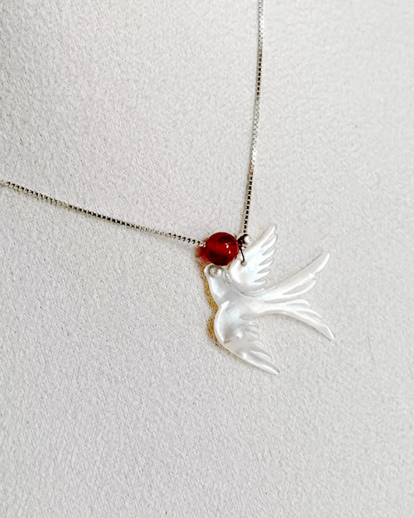 Close-up of mother-of-pearl phoenix with iridescent shimmer, paired with vibrant 6mm red agate