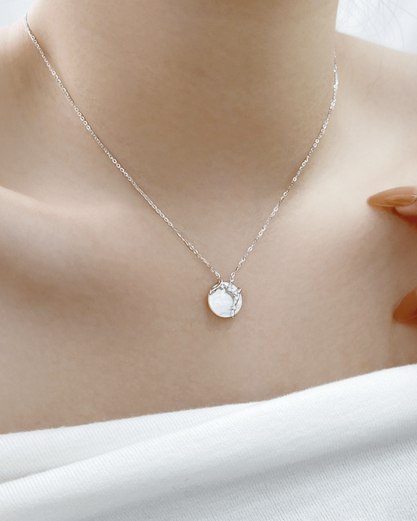 Model wearing mother-of-pearl crescent necklace styled with minimalist daytime outfit, embodying Eastern cosmic balance