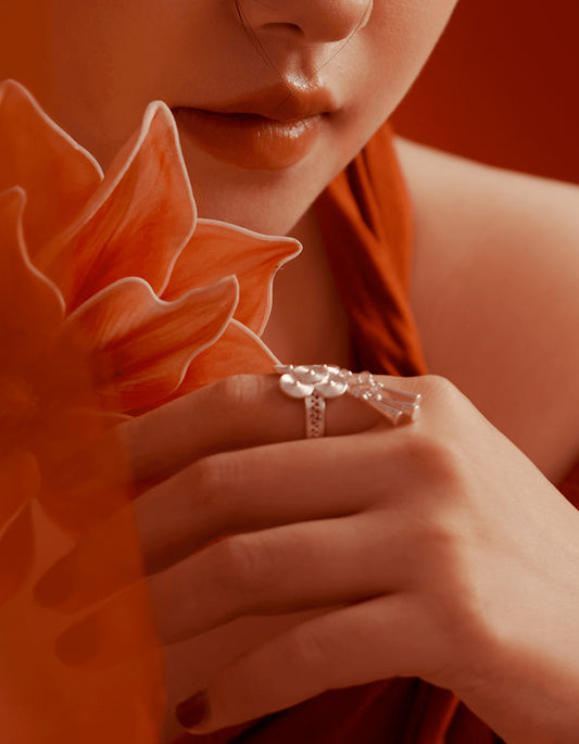 Close-up of ZolanJewelry silver lotus bell statement ring, silver bells gently hanging and catching light, conveying soft movement and ritual depth