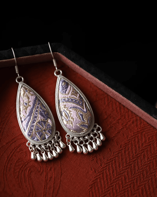 Flat lay of Song brocade teardrop earrings with gradient indigo silk and engraved silver cloud frame
