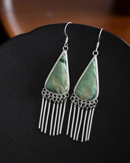 Detail shot of lightweight earrings combining featherlight fabric with bold geometric silver structure