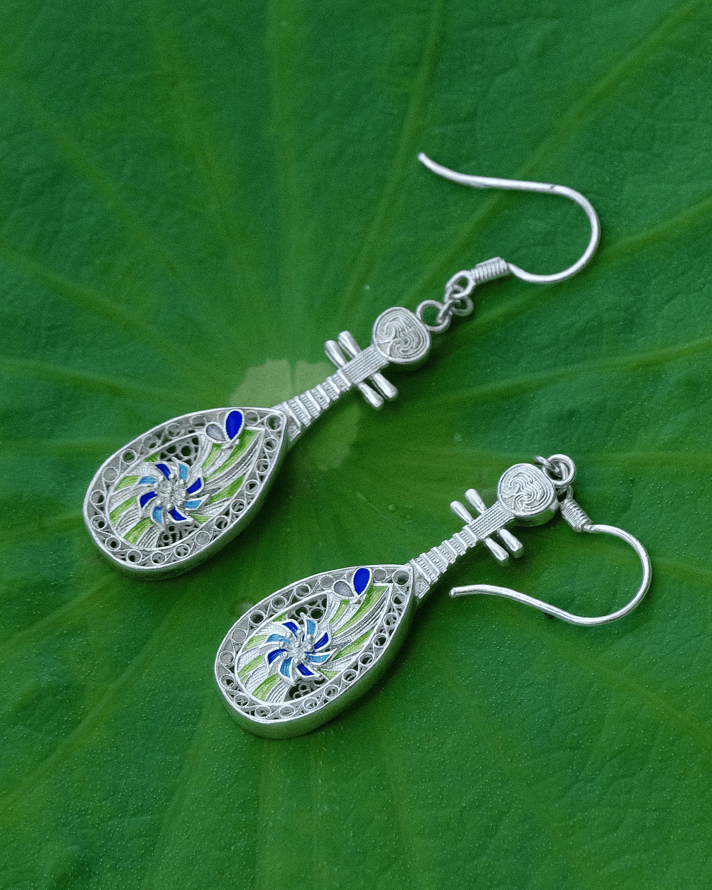 Close-up of handmade silver pipa earrings with lotus and enamel details — symbolic Oriental jewelry rooted in traditional Chinese craftsmanship.
