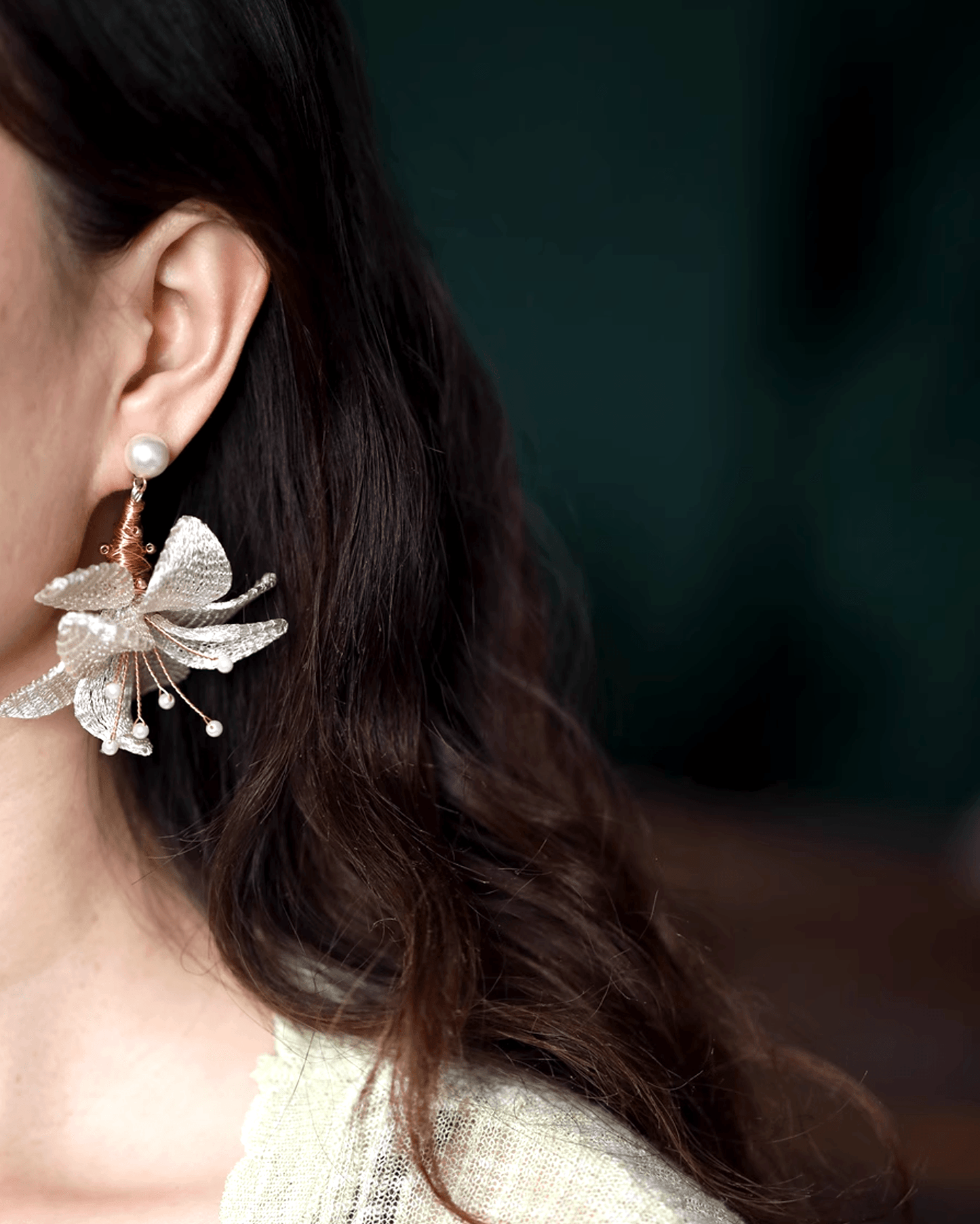Side profile of earrings styled for formal event, mesh petals catching ambient light