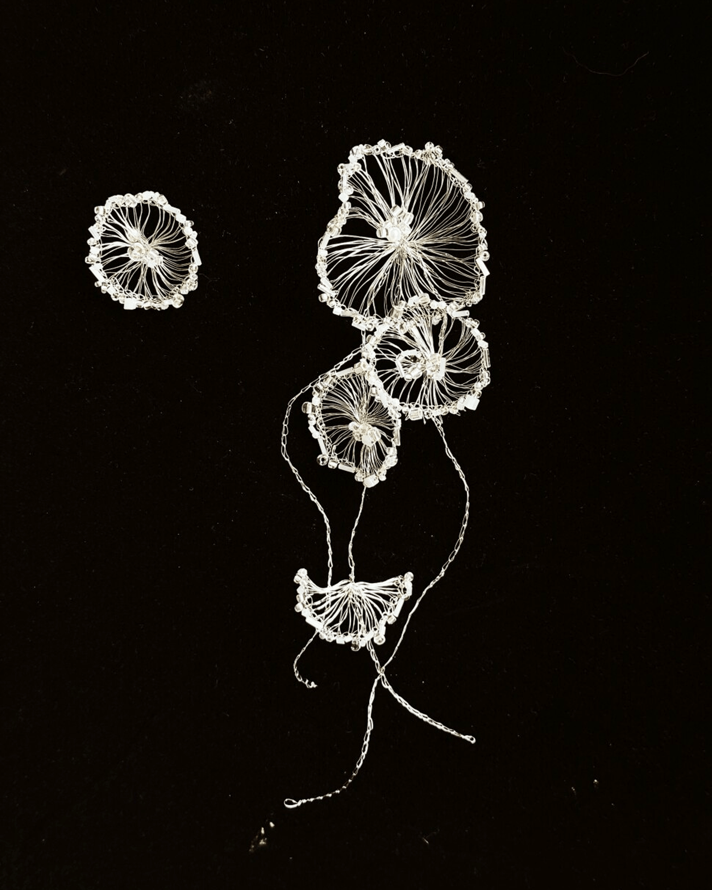 Close-up of silver-plated crocheted wire forming fluid, tentacle-like shapes on long dangle earrings