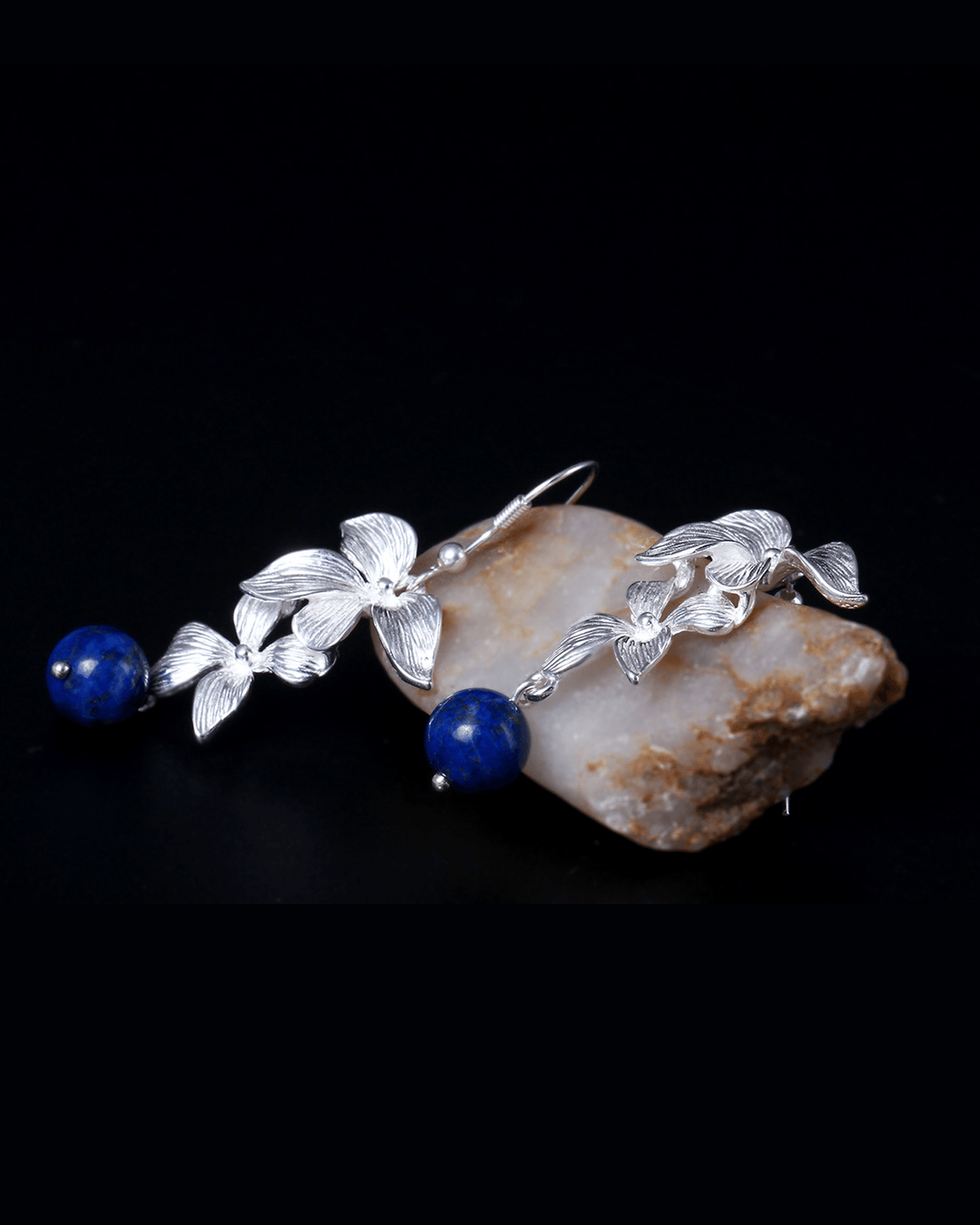 Flat lay of celestial orchid earrings featuring hand-cut 6mm natural lapis lazuli stones with golden pyrite flecks, set in sterling silver filigree petals