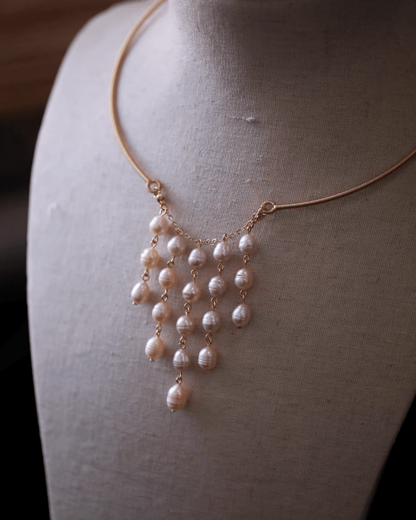 Close-up of pearls brushing collarbone on bare décolletage, capturing subtle femininity