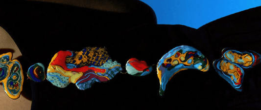 Colorful cloisonné enamel jewelry pieces arranged in a row, showcasing intricate patterns and vibrant traditional designs