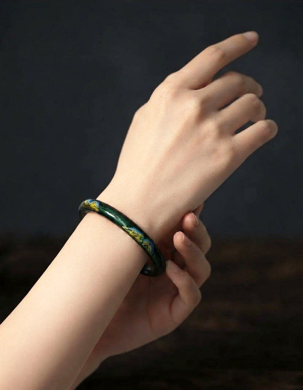 Model wearing the A Thousand Li Chinese lacquer bangle, highlighting its elegant silhouette, lightweight design, and deep green and gold finish