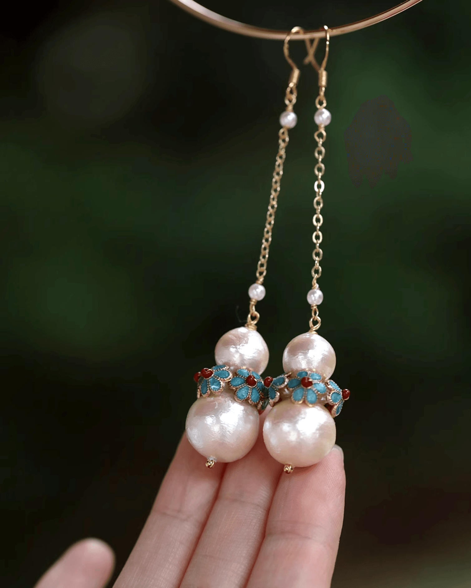 Flat lay of cotton pearl earrings paired with handcrafted cloisonné floral rings featuring turquoise and red enamel