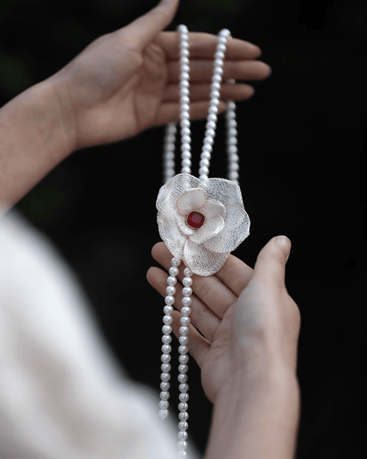 Flat lay of shell pearl necklace with detachable mother-of-pearl camellia brooch, inspired by Qing dynasty marine chronicles