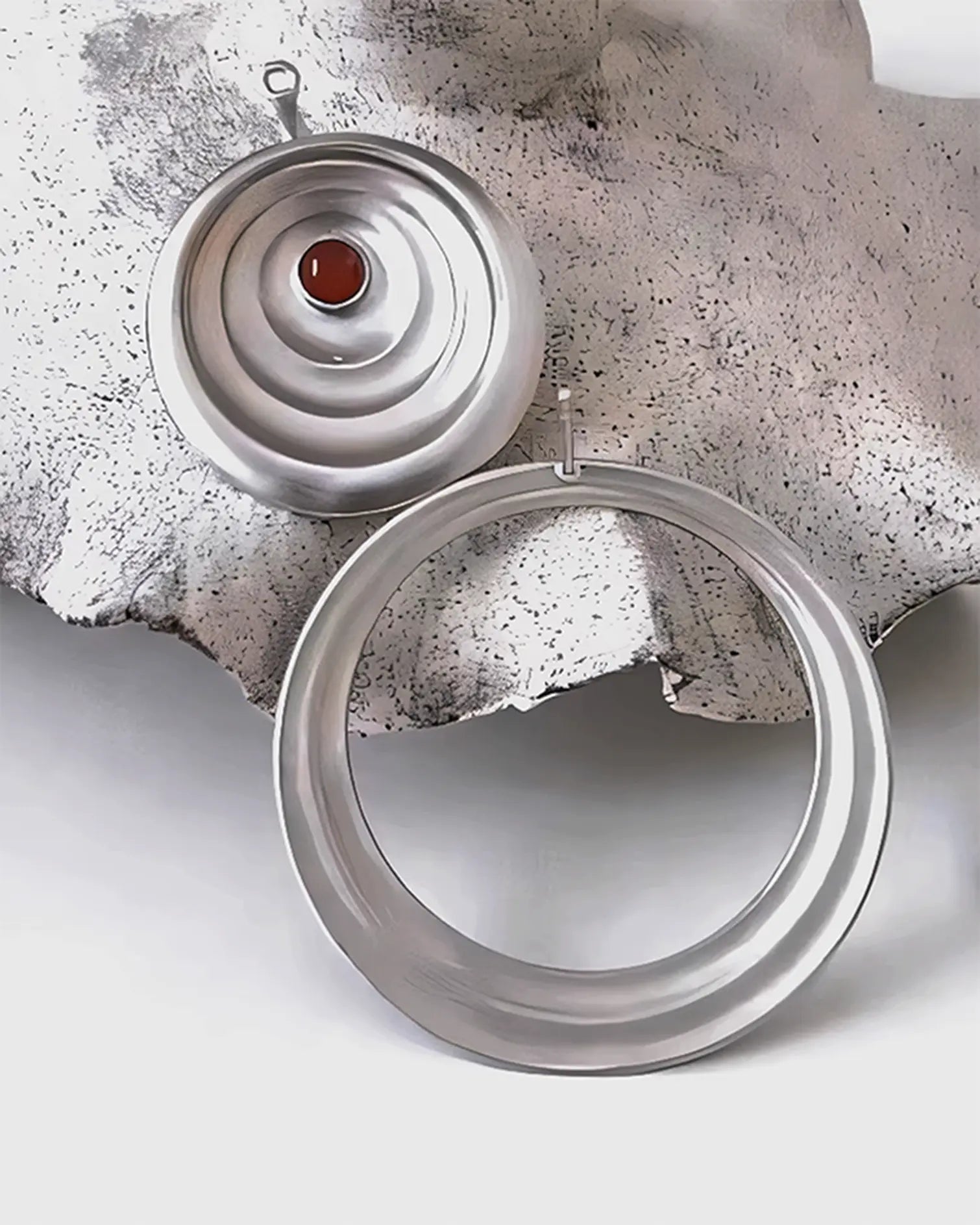 Close-up of detachable silver earring stud showing precise hand-engraved water ripple pattern and smooth polished edges