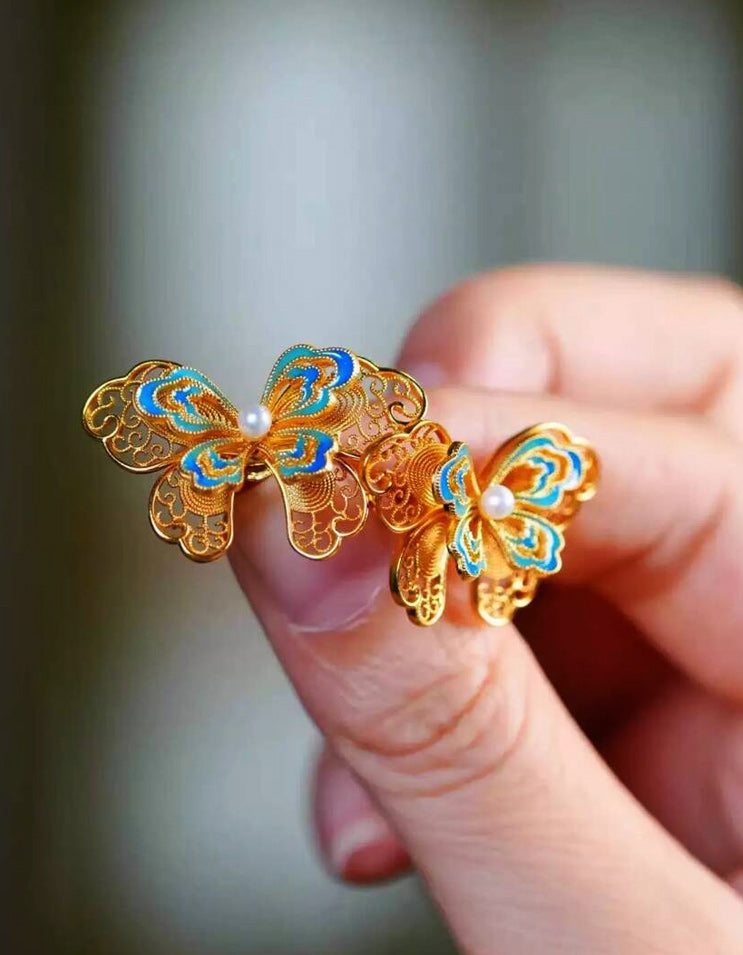Close-up of pearl butterfly earrings in huasi xiangqian filigree setting