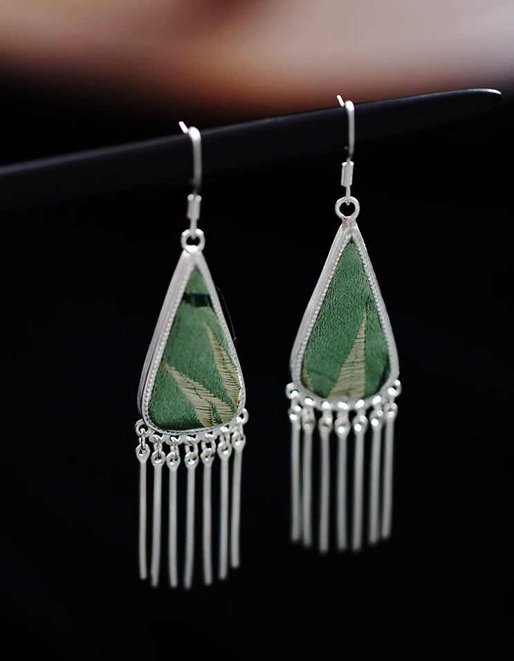 Handcrafted Chinese textile jewelry featuring jade-toned song brocade and silver tassels. Featherlight triangle earrings blending ancient silk art.