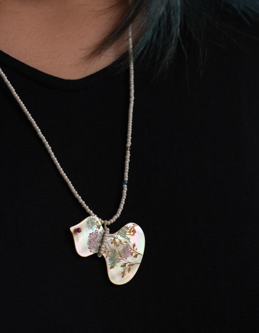 Model wearing the Fortune in Bloom Chinese lacquer necklace, with a yellow mother-of-pearl gourd pendant hand-painted with chrysanthemums.
