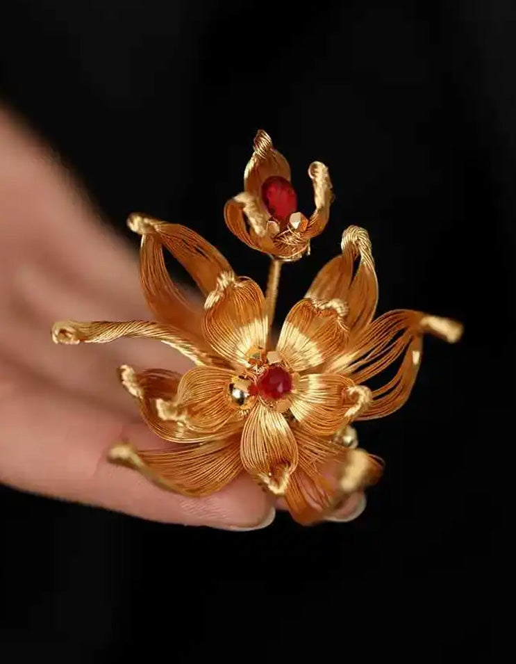 Close-up of a gold pear blossom brooch crafted in fine Chinese filigree, showing intricate petal details.