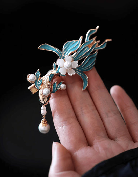 An artistic manifestation of heritage Jingtailan technique. This handcrafted blue koi cloisonné hair clip features mineral glazes and luminous pearl work.