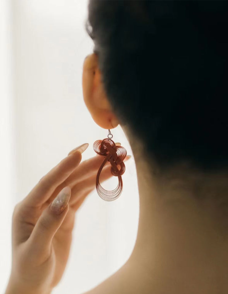 Model wearing bamboo-woven earrings in a natural, warm setting