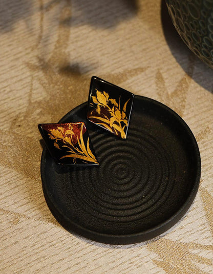 Side angle of the lacquer earrings highlighting the glossy surface and geometric silhouette.