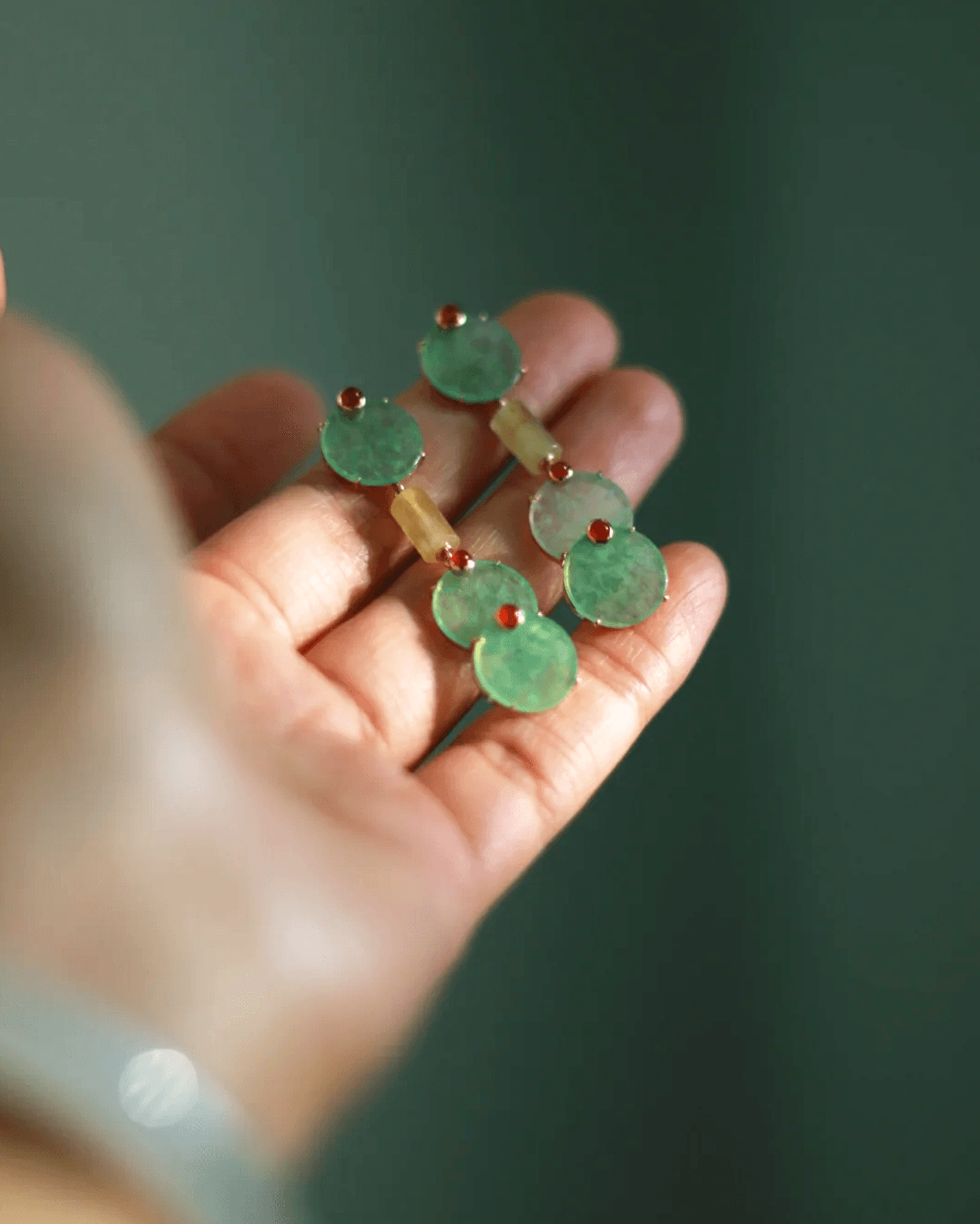 Flat lay of Harmony Trio earrings with three green chalcedony discs and 14K gold-plated pillar, inspired by Chinese cosmology