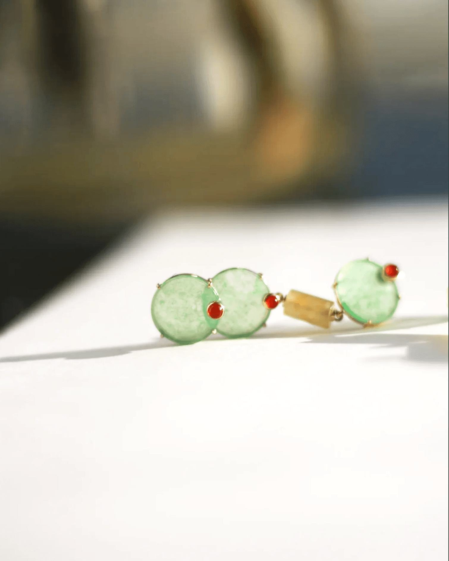 Detail shot of 14K gold-plated column with micro cloud carvings and suspended green gemstone trio