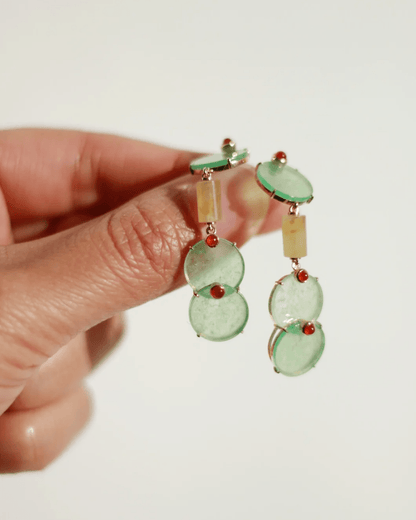 Close-up of earrings in motion, showing light catching the jade’s glow and carnelian’s spark