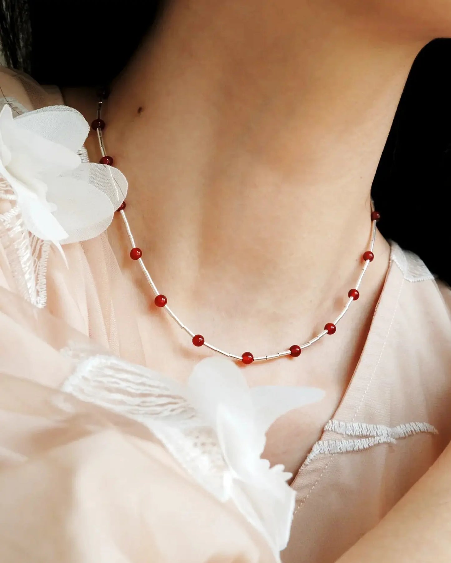 Side view of necklace styled with deep V-neck top, highlighting red gemstone glow and silver movement