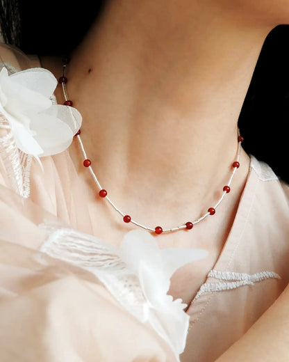 Side view of necklace styled with deep V-neck top, highlighting red gemstone glow and silver movement