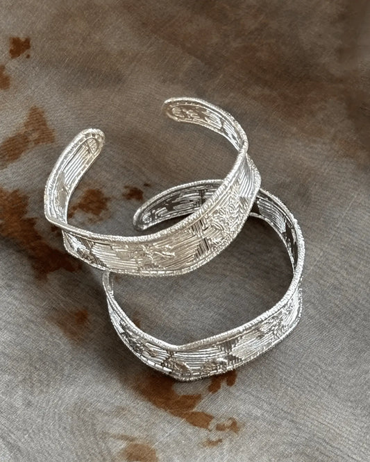 Flat lay of filigree silver bangle with gardenia petal openwork, inspired by Chinese heritage metalwork