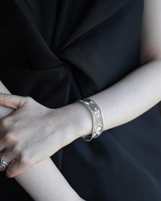 Side view of silver gardenia cuff resting on wrist, reflecting crescent moon shape and delicate craftsmanship