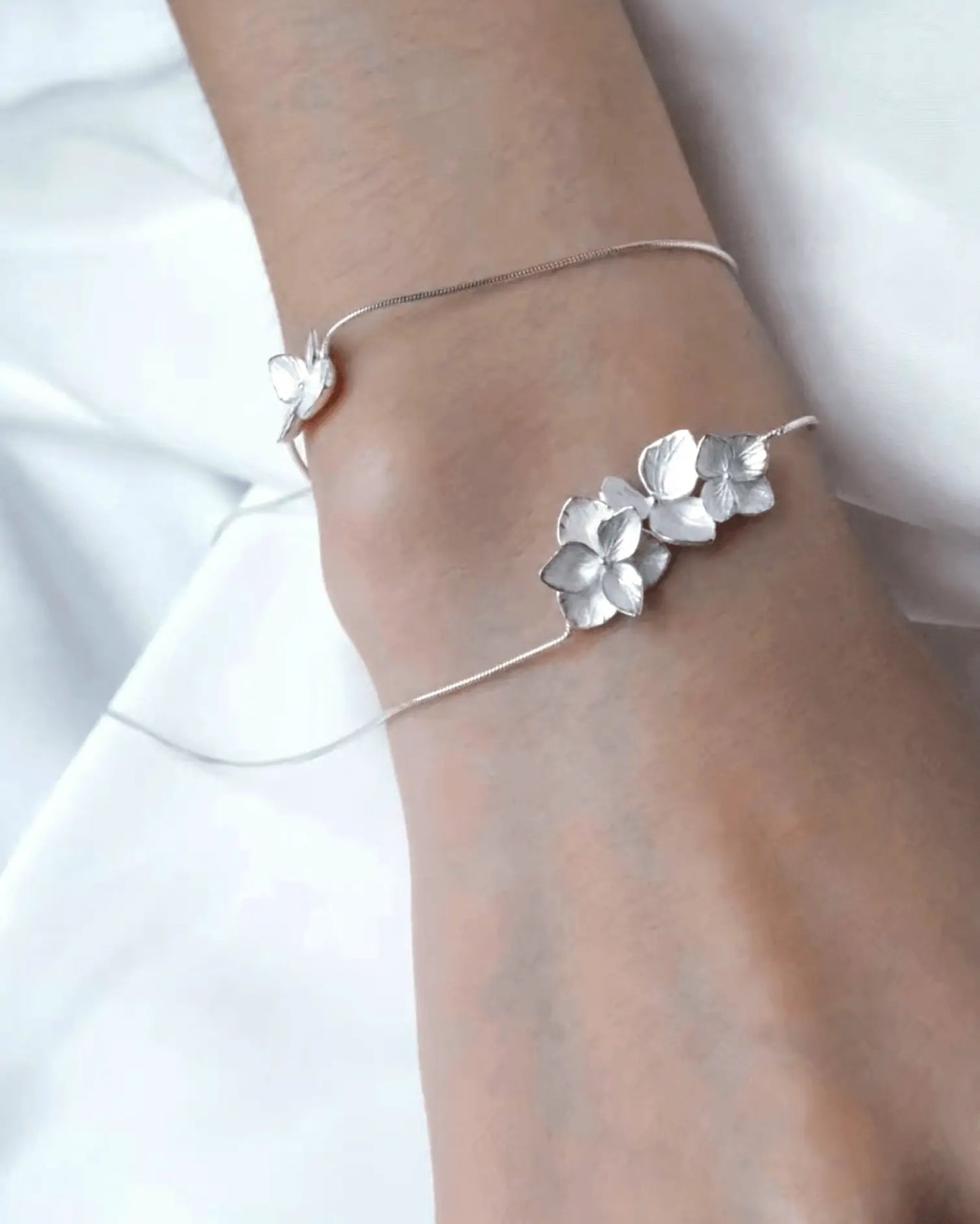 Flat lay of sterling silver hydrangea petal necklace with alternating matte and glossy finishes, inspired by Eastern floral gardens