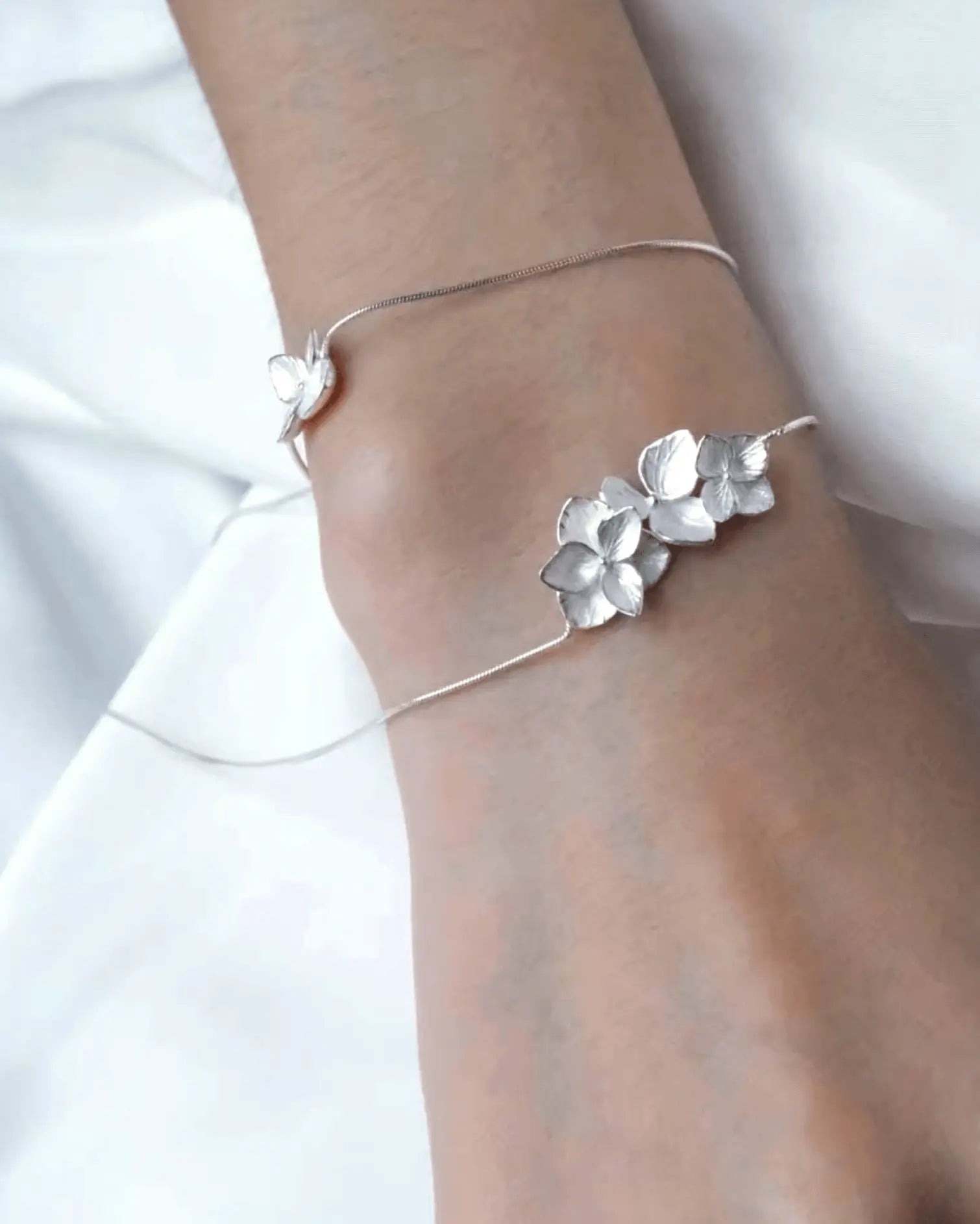 Flat lay of sterling silver hydrangea petal necklace with alternating matte and glossy finishes, inspired by Eastern floral gardens