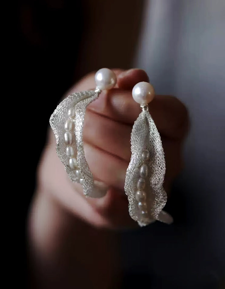 Handwoven silver mesh earrings cradling freshwater pearls like dew in silk pods. A poetic fusion of Eastern symbolism and minimalist elegance.