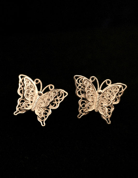 Close-up of handmade filigree earrings with 0.2mm silver wires forming butterfly wings
