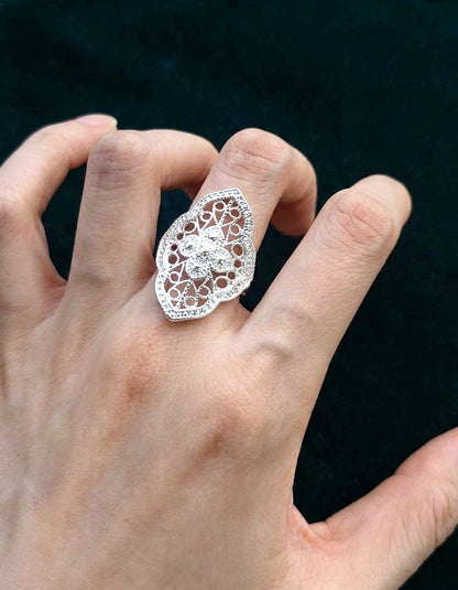 Sterling silver ring placed on embroidered cloth with Yi ethnic symbols and aged wood background, honoring Chinese huasixiangqian craft roots