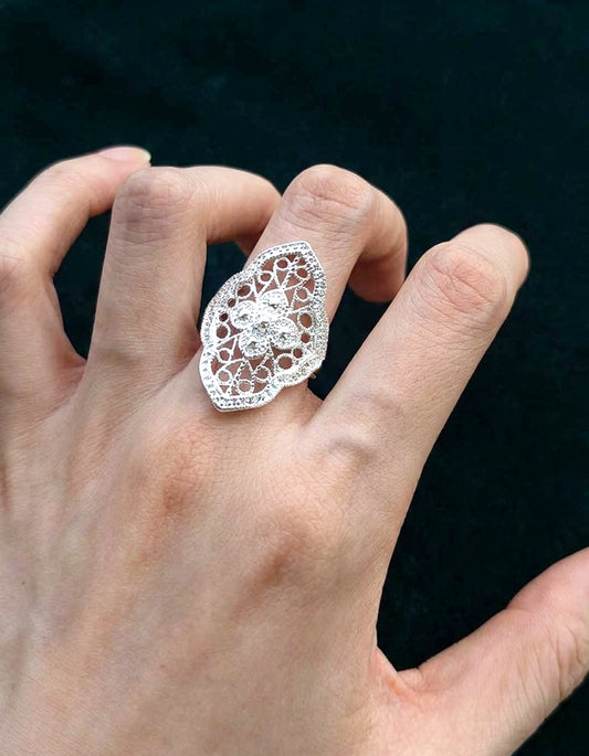 Sterling silver ring placed on embroidered cloth with Yi ethnic symbols and aged wood background, honoring Chinese huasixiangqian craft roots