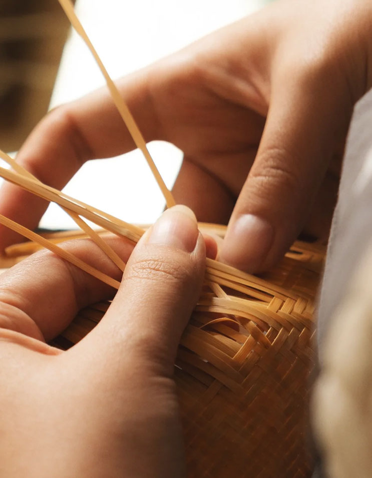 Artisan weaving bamboo by hand, showing traditional techniques and detailed craftsmanship