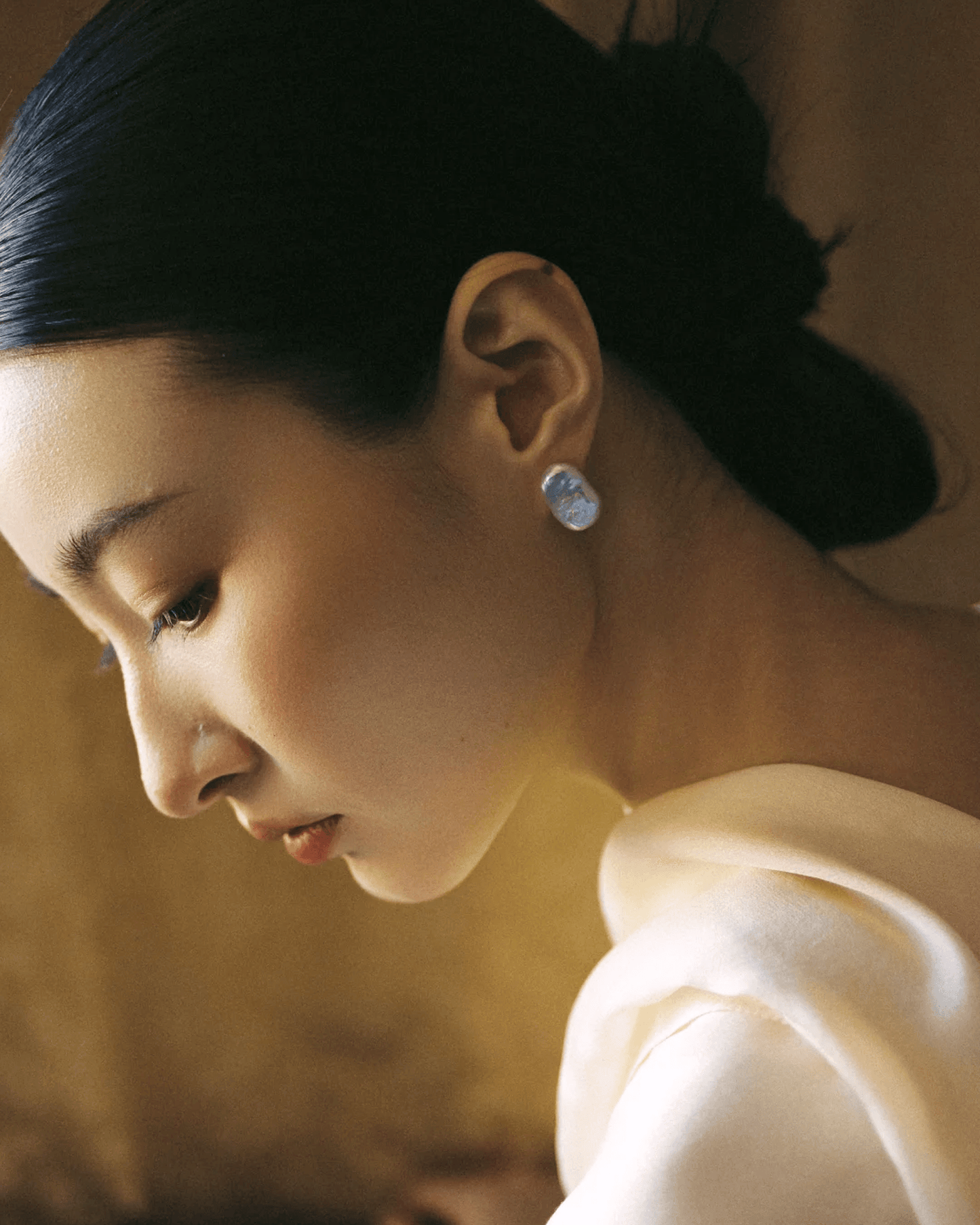 Model wearing baroque pearl earrings with slick minimalist outfit, modern interpretation of yin-yang duality