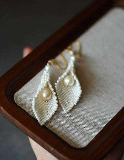 Macro shot revealing the fine weaving and natural pearl glow of ZolanJewelry calla lily earrings.