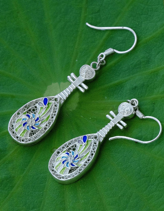 Close-up of handmade silver filigree pipa earrings.